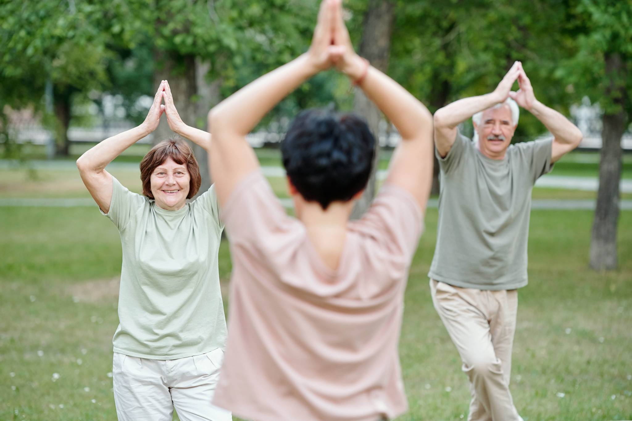seniorzy w podeszłym wieku ćwiczący jogę w parku